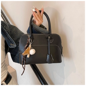 Detail of black PU leather handbag featuring white contrast stitching and baseball charm