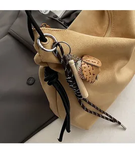 Détail du pendentif baseball avec batte et gant sur un sac à bandoulière en daim