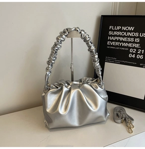 Detail of silver pleated cloud bag with metallic finish and adjustable shoulder strap