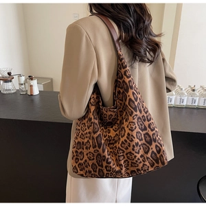 Detail of leopard print tote bag featuring brown leather strap shown on a model