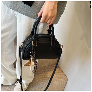 Detail der schwarzen PU-Schultertasche mit Baseball-Anhänger und goldenem Reißverschluss-Design