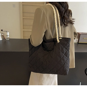 Close-up of black quilted tote bag with white cotton rope handles and silver metal hardware