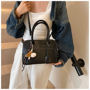 Close-up of black PU leather bag featuring white contrast stitching and baseball charm