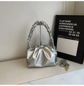 Detail of silver metallic pleated cloud bag featuring ruched handle and detachable strap
