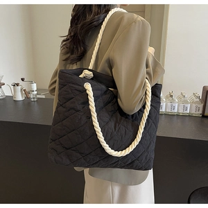 Detail of black quilted tote bag with thick white woven cotton rope shoulder strap