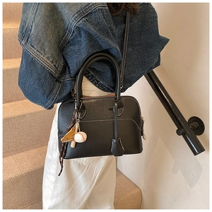 Detail of minimalist black PU leather bag with baseball charms and textured finish