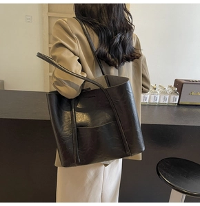 Detail view of stylish black PU leather tote bag with vintage texture and slim straps