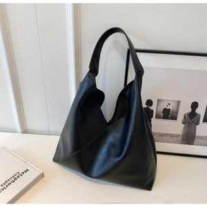 Close-up detail of soft faux oil wax leather texture and triangle stitching on black tote bag