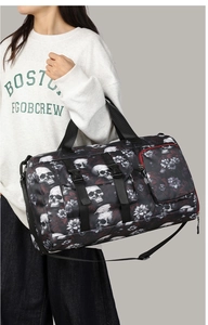 Détail d'un sac cabas noir avec imprimé tête de mort et fleurs, poches et bandoulières