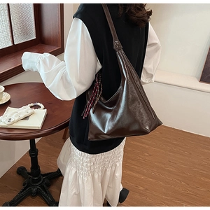 Detail of dark coffee Hobo bag showing glossy faux leather texture and weaving pendant