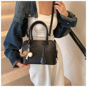 Detail of black pebbled PU leather handbag with white stitching and baseball charm