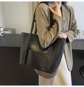 Detail of a large black tote bag with vintage wrinkled texture and dual shoulder straps