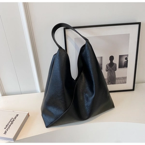 Detail of soft black leather texture and integrated strap on minimalist tote bag