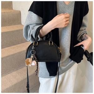 Detail der schwarzen PU-Leder Boston Bag mit goldener Hardware und Baseball-Anhänger