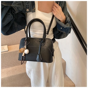 Detail view of black PU shell bag with white contrast stitching and baseball bag charm