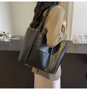 Detail of a large black matte PU leather tote bag with a crinkled texture worn over the shoulder
