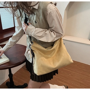Détail du sac hobo en daim jaune gingembre avec large bandoulière et bijou de sac