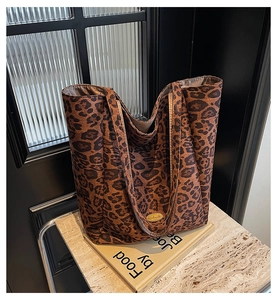 Close-up of leopard print canvas tote bag with a golden handmade metal emblem detail