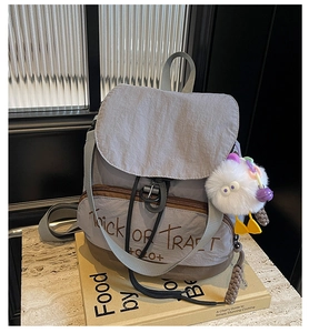 Détail du sac à dos en nylon lilas avec broderie rétro et breloque en peluche sur pierre