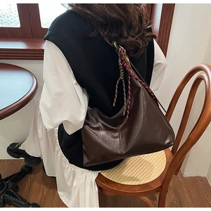 Detail of dark brown faux leather tote bag with colorful braided rope strap accent