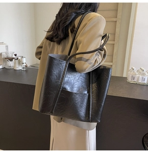 Detail of black textured PU leather tote bag with long shoulder straps and front pocket