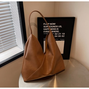 Detail of caramel brown faux leather shoulder bag with vintage crinkle texture and triangle design