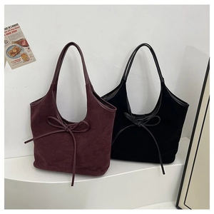 Détail des sacs fourre-tout en daim bordeaux et noir avec des nœuds décoratifs élégants