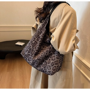 Close-up of leopard print tote bag with black leather handles on a beige trench coat