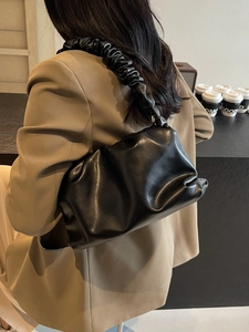 Chic black pleated cloud bag with scrunchie shoulder strap for women in modern cafe setting