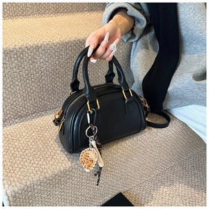 Detail einer schwarzen PU-Leder Bowlingtasche mit Goldbeschlägen und Strohhut-Anhänger