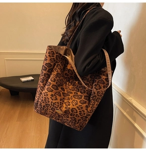 Detail of leopard print tote bag with golden metal logo tag and wide shoulder strap