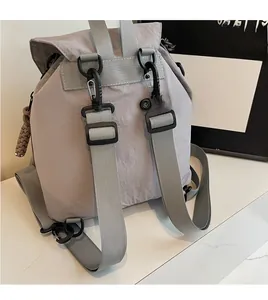 Détail du sac à dos en nylon gris clair avec bretelles réglables sur marbre