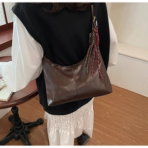 Detailed back view of a dark brown PU leather crescent shoulder bag with colorful braided tassel
