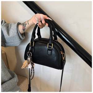 Detail der schwarzen halbrunden PU-Leder Handtasche mit Goldschnalle und Baseball-Anhängern