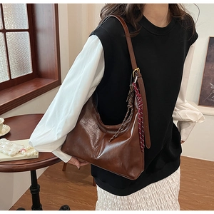 Detail of dark brown glossy leather Hobo bag with side woven rope and fringe tassels