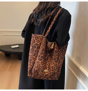 Detail view of large leopard print velvet tote bag with handmade label on model's shoulder