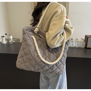 Close-up of quilted grey tote bag featuring thick cotton rope handles and metal eyelets
