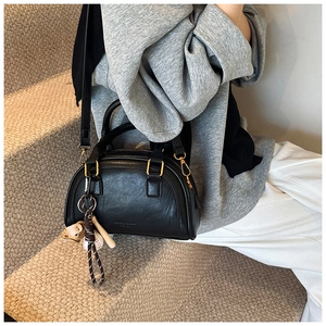 Detail der schwarzen PU-Leder Boston-Tasche mit Goldbeschlägen und Baseball-Anhänger