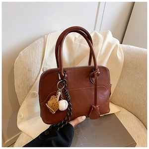 Chic brown PU leather crescent shoulder bag with baseball charm on white blazer