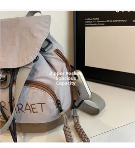 Vue détaillée de la poche latérale zippée d'un sac à dos en nylon gris pour ranger un portable