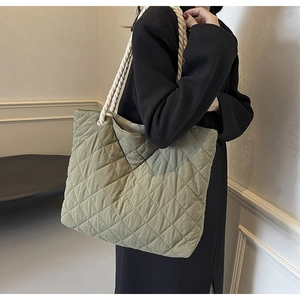 Sage green quilted tote bag with chunky white rope handles shown on a model