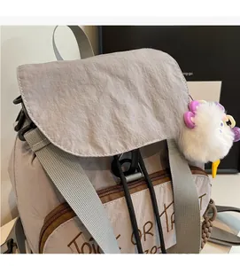 Détail du sac à dos gris d'automne montrant la broderie Trick or Treat et le pompon blanc