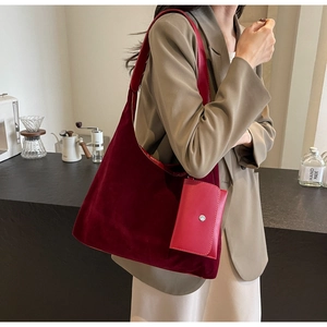Detail of dark red velvet tote bag with matching coin pouch on a minimalist model