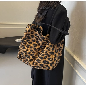 Close-up of leopard print quilted tote bag with black shoulder straps and diamond stitching
