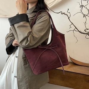 Sac hobo chic en daim mat bordeaux avec détail de nœud présenté dans un décor lifestyle