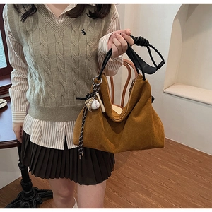 Détail du sac hobo en daim caramel avec pendentif de baseball et poignée noire