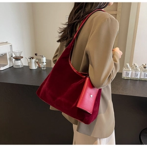 Detail of burgundy velvet tote bag with matching leather pouch in a cafe setting
