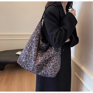 Close-up of leopard print tote bag with black leather straps on elegant black coat