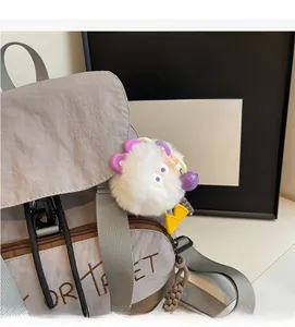Détail du sac à dos en nylon gris avec un porte-clés monstre en peluche blanc mignon