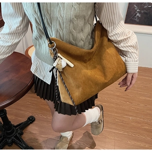 Vue détaillée d'un sac hobo en daim marron avec fine bandoulière noire et pendentif